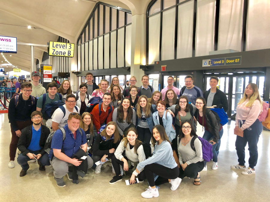 A group of people gathered in an airport at the ticket counter