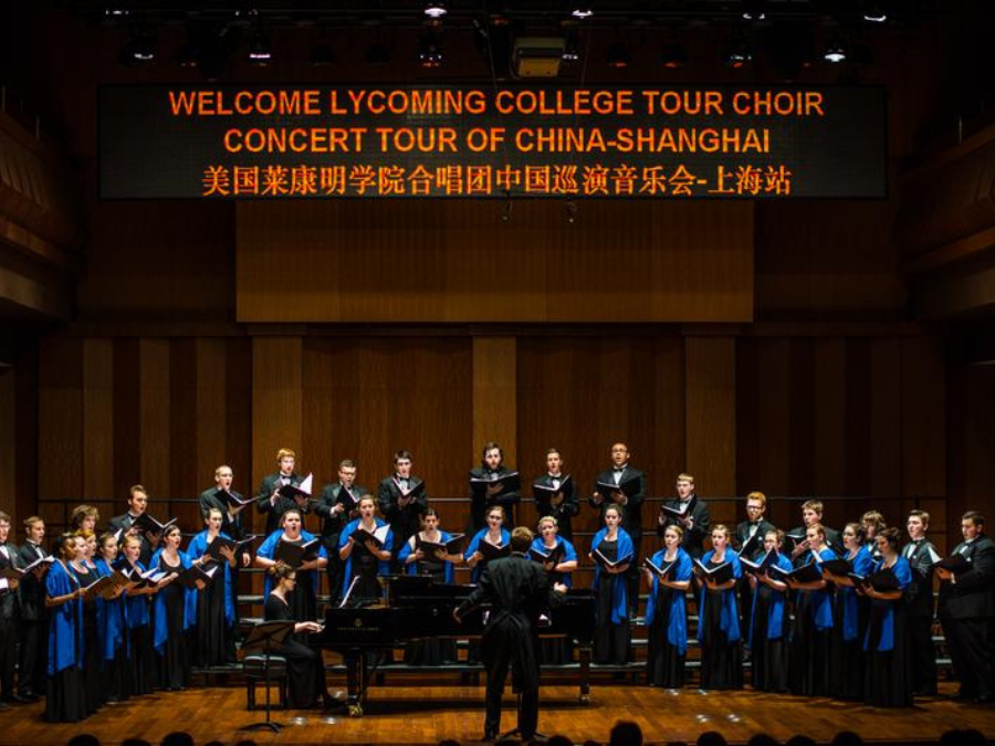 A choir dressed in black with blue scarves performing on stage in China