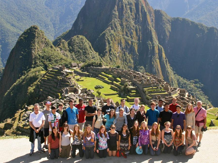 A group of teenage tourists with adult leaders standing in front of Machu Picchu in Peru