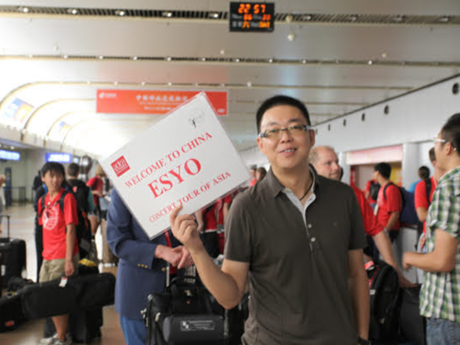 A man holding a sign leading a group through an airport