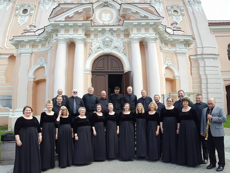 A choir dressed in black standing in front of a church