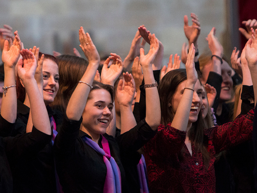 A choir singing with their arms raised